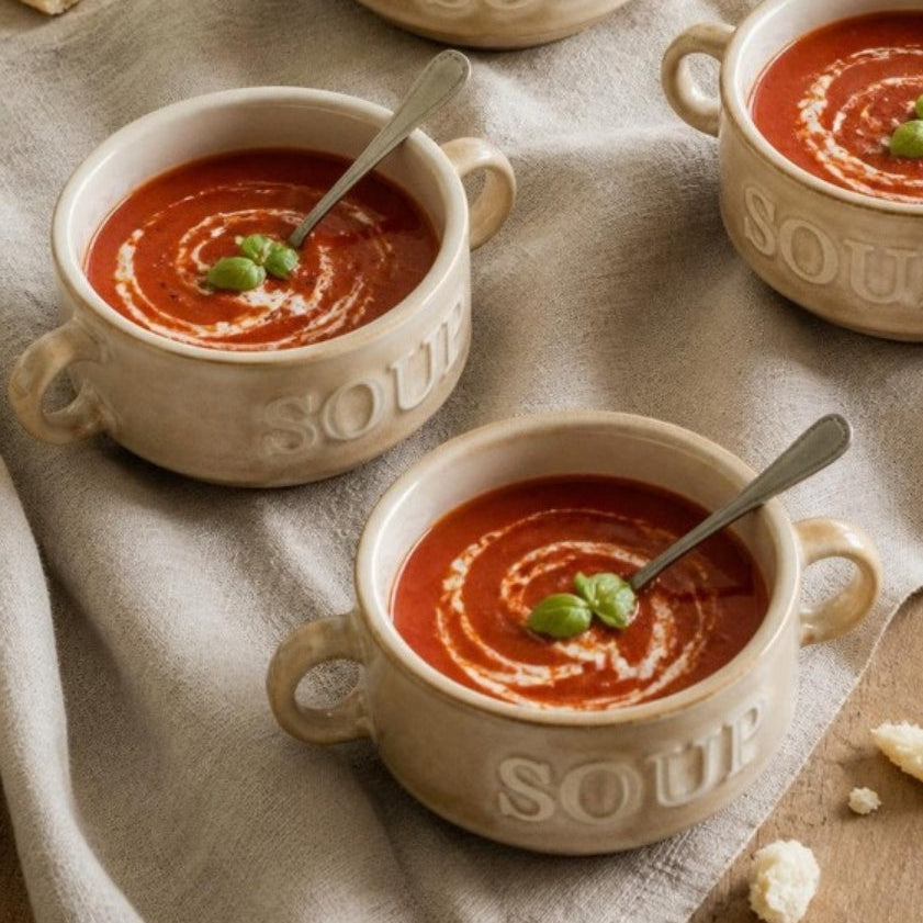 Vier crème Soup soepkommen met tomatensoep op een gedekte tafel, van bovenaf